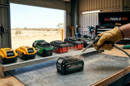 Professional power tool battery care: using a compressed air tool to safely clean terminals on a cordless battery in an Australian workshop.